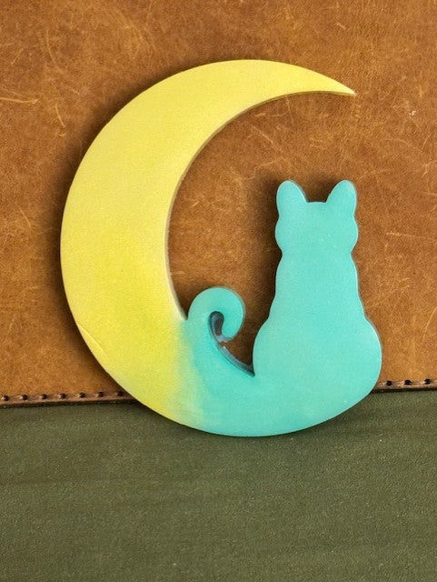 Decorative item with a cat on a crescent moon design on a brown and green background